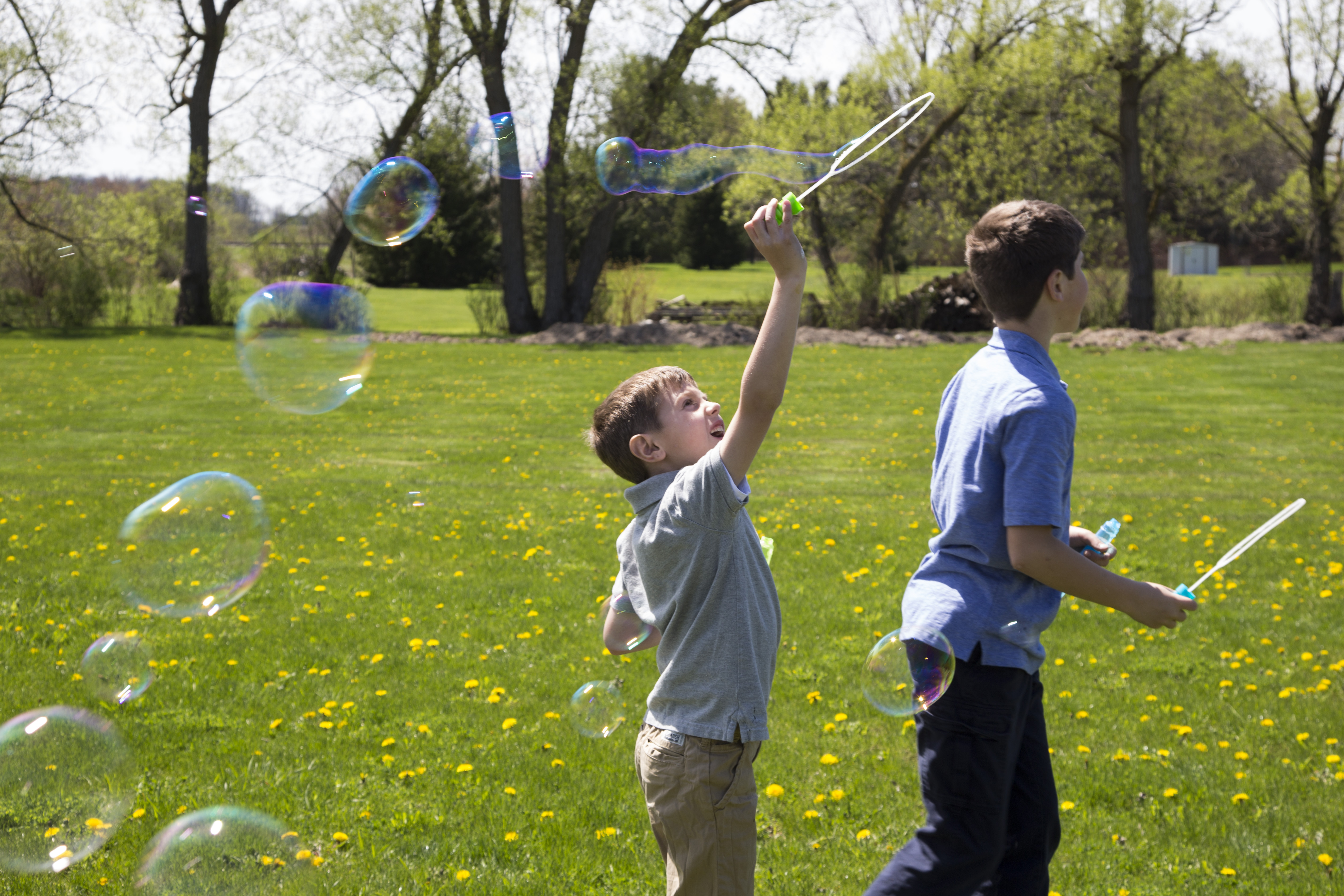 two boys playing with bubbles outside