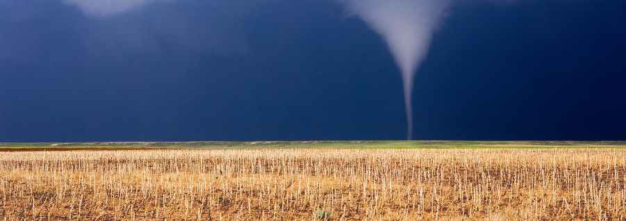 Image of a Dark Sky above a farm field with tornado funnel cloud
