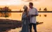 Two people standing in water at sunset 