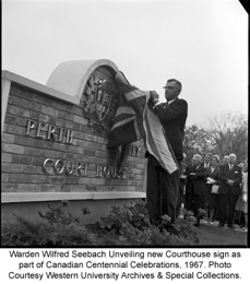 Black and white negative of Warden Wilfred Seebach Unveiling new Courthouse sign as part of Canadian Centennial Celebrations, 1967